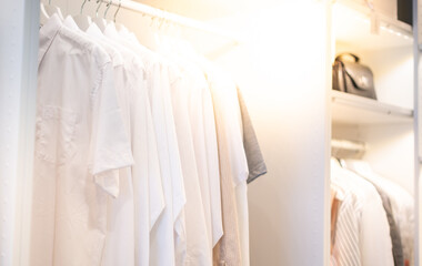 The white shirts hanging on a rack in built-in cupboard for neat and clean the room.