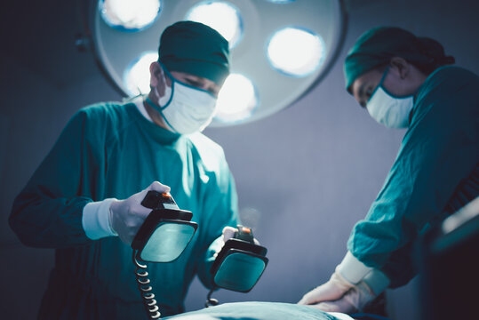 Medical urgency doctor using defibrillator during surgical operation a patient in hospital operating room - Powered by Adobe