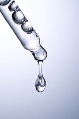 Pipette with serum or other cosmetic product on a blue background.