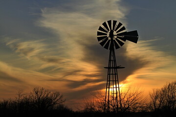 windmill at sunset with clouds and a colorful sky north of Hutchinson Kansas USA out in the country.