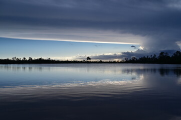 Beautiful late afternoon cloudscape over Pine Glades Lake in Everglades National Park, Florida reflected in lake's calm water.