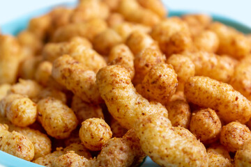 Puffed corn peanuts snacks on plate. Close-up.