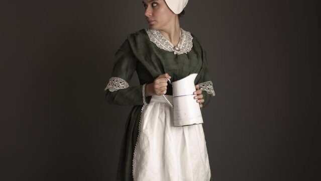 A Victorian maid servant carrying a jug in a darkened room. A candle light filter has been added.