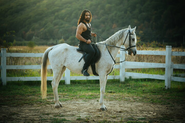 Muscular torso of a male rider on horseback. Horse riding. Sexy man stallion on horse in the countryside.