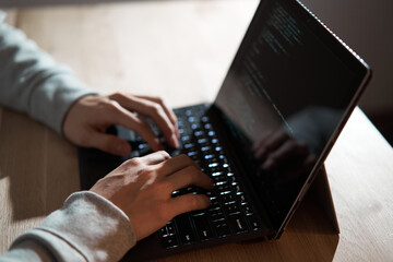 ノートパソコンでコードを書く男性ハッカー