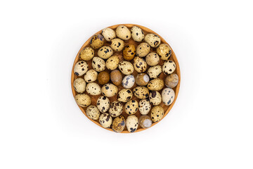 Raw quail eggs on a white background on a plate, top view, healthy eating concept