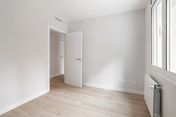 Empty room with door, window, and heating radiator in a white interior house