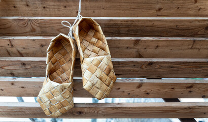 Birchen woven bast shoes hang on a log wall.
