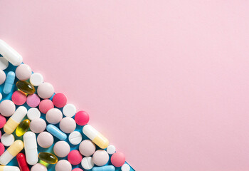 Colorful pills and capsules on pastel pink background. Health, pharmaceuticals and medicine concept. Top view, flat lay, copy space