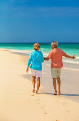 Mature couple walking barefoot on sandy beach Bahamas