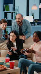 Multi ethnic group of people using joysticks to play video games on tv console for entertainment after work. Workmates playing game with controllers on television to do fun activity.