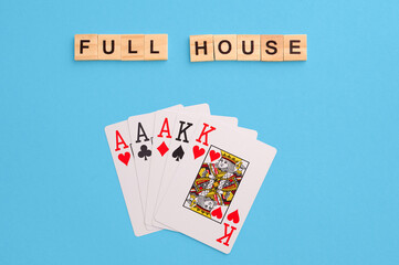 Full house combination. Poker Playing Cards on blue background with wooden blocks. Flatlay, copy space, concept