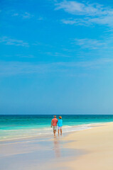 Paradise island view with mature couple walking together