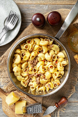 Pasta Pipe Rigate with stew In Bianco in a frying pan on a gray wooden culinary background. Traditional Italian pasta with ground beef on the kitchen table	