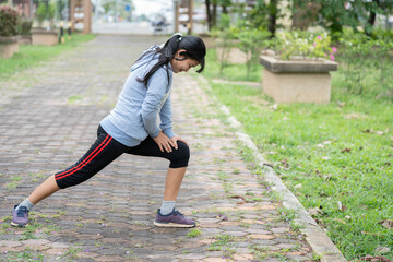 A young asian woman do stretching legs before running in city park.Stretch your body before running.
