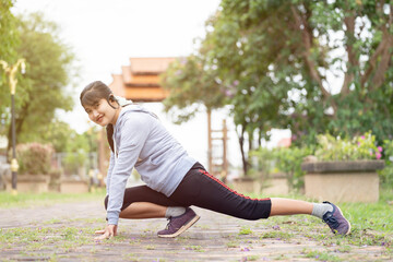 A young asian woman do stretching legs before running in city park.Stretch your body before running.