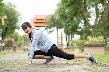 A young asian woman do stretching legs before running in city park.Stretch your body before running.