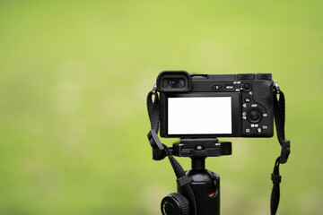 Mirrorless camera with green screen on monopod, white screen camera