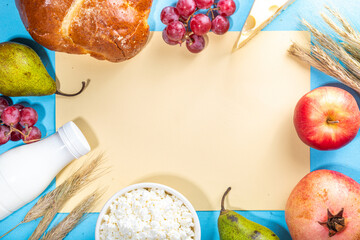 Happy Shavuot greeting card background with food Symbols of jewish Shavuot holiday - pomegranate, grapes, apple, sweet challah bread, wheat spikelets, milk, cheese, cottage cheese, on light blue backg