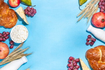 Happy Shavuot greeting card background with food Symbols of jewish Shavuot holiday - pomegranate, grapes, apple, sweet challah bread, wheat spikelets, milk, cheese, cottage cheese, on light blue backg