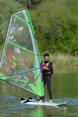 young man windsurfing on a lake