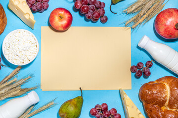 Happy Shavuot greeting card background with food Symbols of jewish Shavuot holiday - pomegranate, grapes, apple, sweet challah bread, wheat spikelets, milk, cheese, cottage cheese, on light blue backg