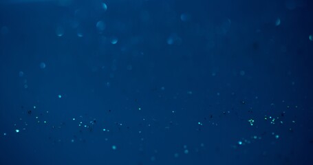 Bokeh glow overlay. Underwater sparkles. Sea bubbles. Defocused blue color shiny round flecks light reflection on dark abstract background.