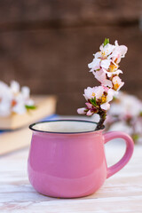 close up beautiful blossom twig of almond tree in a pink cup on the table. spring still life