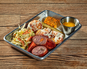 Lunch set of sausage, potato croquettes with creamy dressing, vegetable salad, pickles and grilled corn