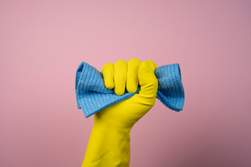 a hand with a yellow rubber glove holds a cleaning sponge