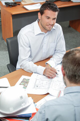 Two men in meeting, plans on the table