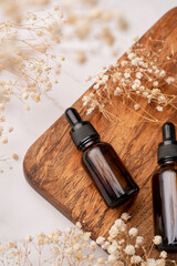 amber glass essential oil dropper bottle with pipette on concrete background with white flowers