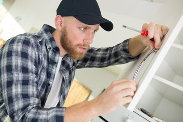 Naklejka na ściany i meble handyman installing kitchen cupboard
