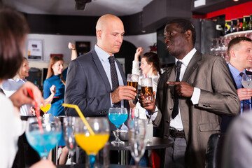 Portrait of African and Caucasian men having fun and talking at a corporate party