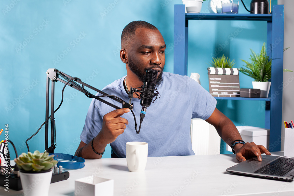 Poster vlogger answering questions talking at professional microphone in vlogging studio reading messages f