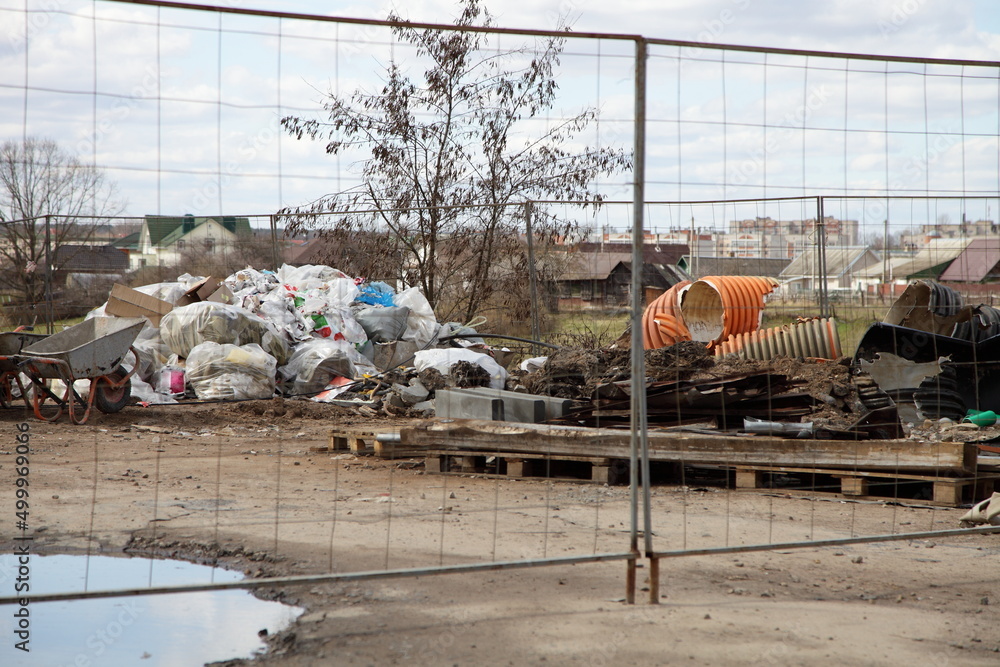 Wall mural industrial garbage pile on construction site with metal net fence