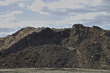 A soil pile on blue cloudy sky background. Building construction and ecology