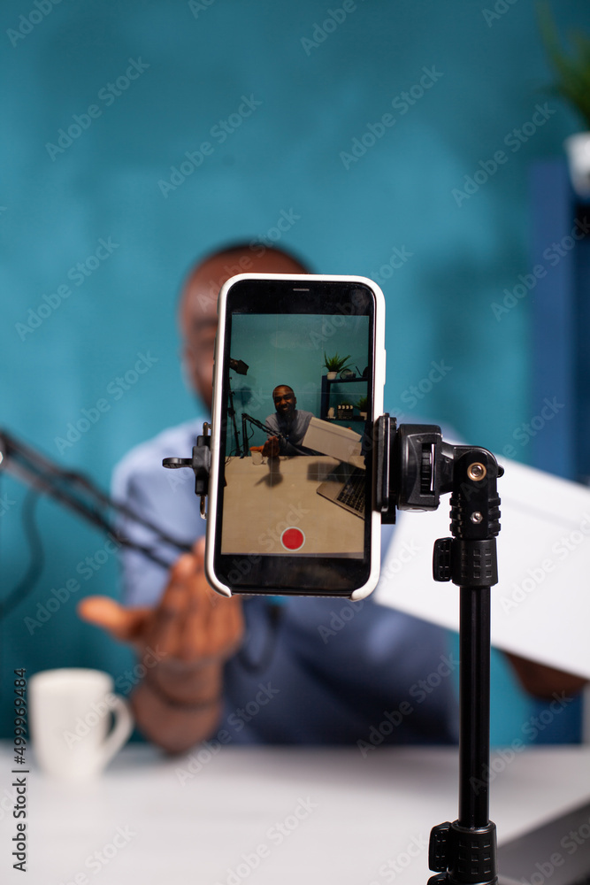 Poster selective focus on mobile phone recording influencer hosting online giveaway holding product box in 