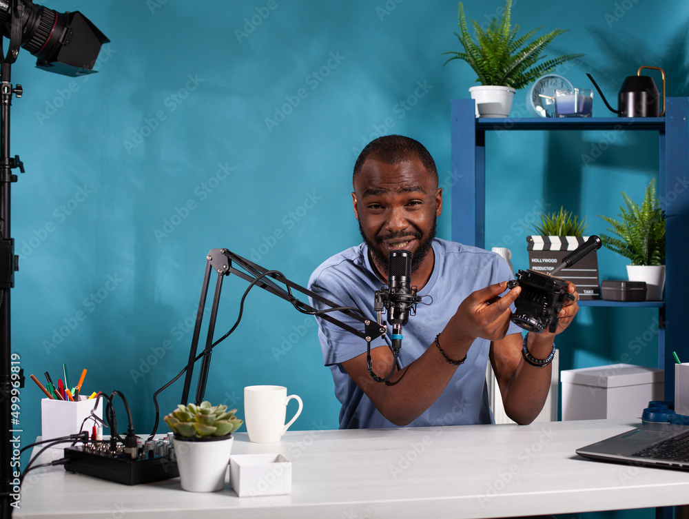 Poster portrait of videographer reviewer presenting fluid tripod head for recording video in vlogging studi