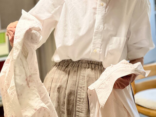 2枚の洋服を選ぶ高齢女性