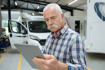 senior man looking at tablet in motorhome garage