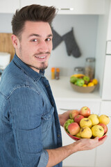 Fototapeta premium young man holding a bowl of fruits