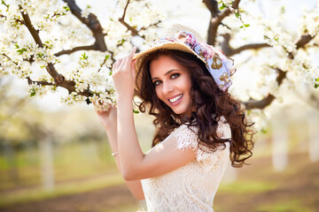 Portrait of a beautiful woman with long hair near flowering trees in spring.