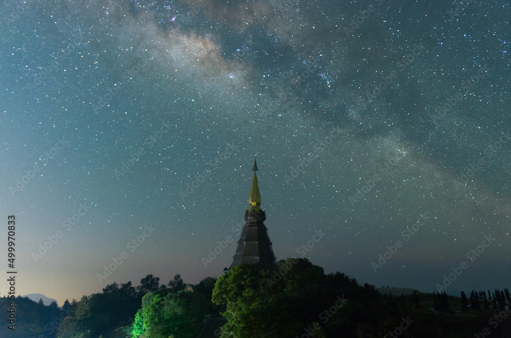 Wall mural the milky way galaxy over a sacred temple at doi inthanon national park, chiang mai, thailand. starr