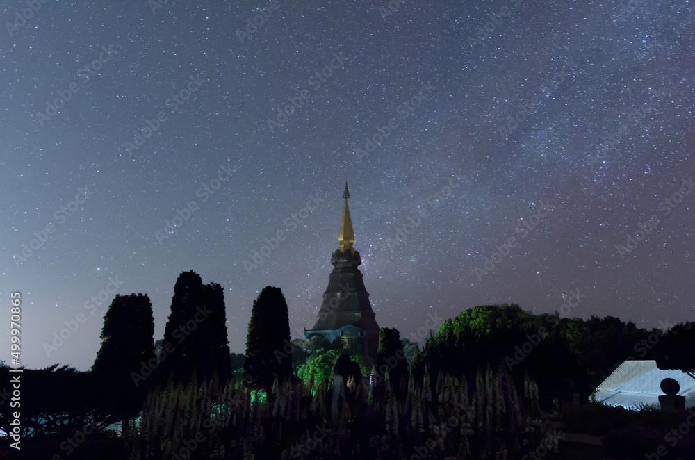 Wall mural the milky way galaxy over a sacred temple at doi inthanon national park, chiang mai, thailand. starr