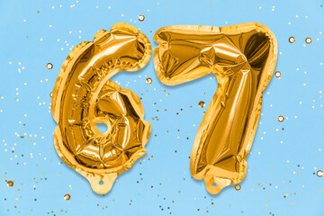 The number of the balloon made of golden foil, the number sixty-seven on a blue background with...