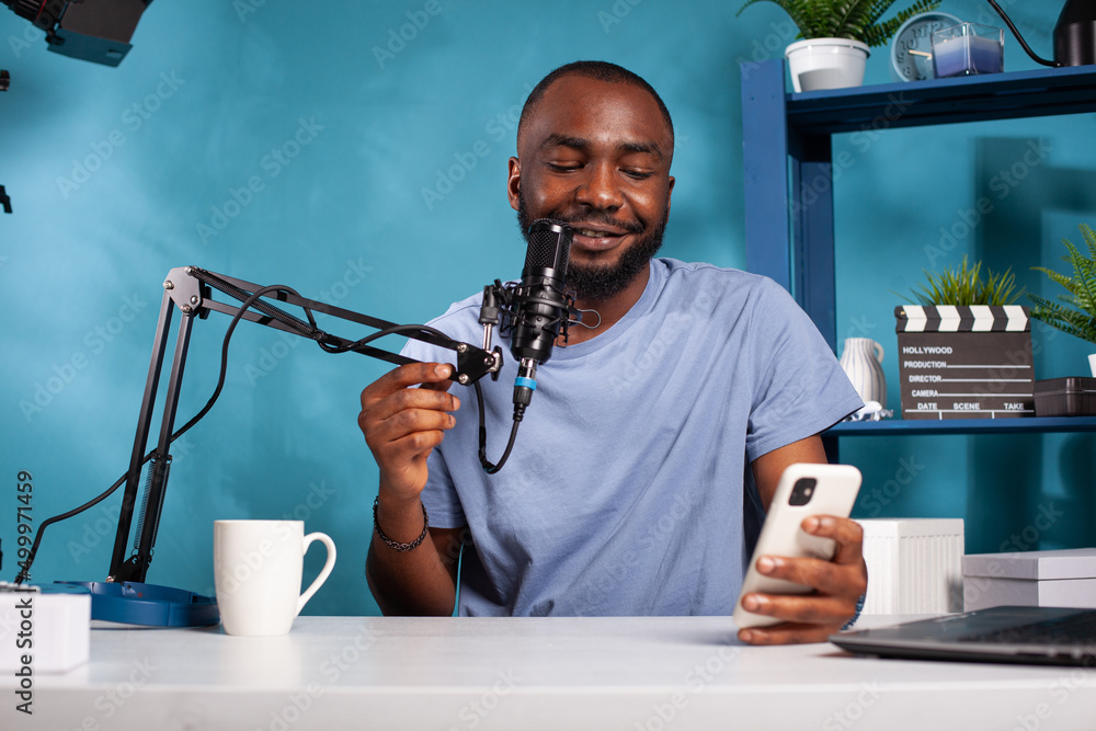 Poster influencer having questions and answers session using microphone in recording desk in vlogging studi