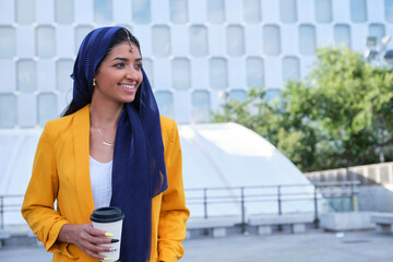 Young indian businesswoman holding a cup of coffee outdoor.