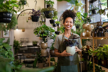 Small business owner smiling in her plant shop - obrazy, fototapety, plakaty