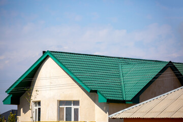 Roofs of houses from a metal profile against the sky. Roofing. Metal tiles on the roofs of houses.